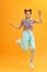 Full length photo of joyful lady jumping high listening modern youngster playlist music through cool earflaps isolated on yellow