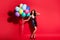 Full length photo of lady hold many balloons hand head wear glossy mini dress high heels isolated vibrant red color