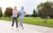 Full-length photo of lovely joyful retirees couple jogging outside in city park