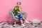 Full length photo of pleasant retired woman wear plaid shirt sit on armchair dreamy look empty space isolated on pink