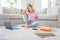 Full length photo of positive cheerful pupil kid sit floor carpet enjoy distance education study homeschool in house
