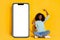 Full length photo of positive pretty lady sit floor direct fingers large empty space telephone isolated on yellow color