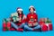 Full length photo of positive tricky women santa elves wear ornament pullovers preparing x-mas gifts isolated blue color