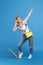 Full length photo of pretty carefree young woman with penny or skateboard listening music with yellow headphones over