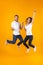 Full length photo of rejoicing couple screaming in surprise while jumping, isolated over yellow background