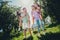 Full length photo of two couples buddies sitting piggyback looking each other outdoors outside backyard forest