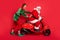 Full length photo of two people elf santa ride moped stuck wear x-mas costume coat cap boots isolated red color