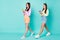 Full length photo of two sisters ladies hold telephone hands chatting buddies walk down street wear cropped sweaters