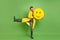 Full length photo of young cheerful man happy positive smile hold paper pinata emoji wear raincoat isolated over green