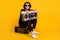 Full length photo of young man hold vintage radio sit boombox wear black t-shirt pants white sneakers sunglass isolated