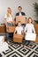 Full-length photo of young married couple with children with cardboard boxes in their hands standing