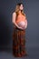 full length portarit of happy young beautiful pregnant woman posing over grey