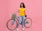 Full length portraif of pretty black lady with vintage bicycle smiling at camera on pink studio background