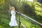 Full length portrait of 5 years old curly beautiful girl in white traditional ukrainian embroidery dress near wooden fence with