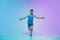 Full length portrait of active young caucasian running, jogging man on gradient studio background in neon light