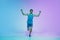 Full length portrait of active young caucasian running, jogging man on gradient studio background in neon light
