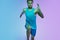 Full length portrait of active young caucasian running, jogging man on gradient studio background in neon light