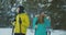 Full length portrait of active young couple enjoying skiing in snowy winter forest, focus on smiling woman in front