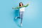 Full length portrait of adorable cheerful lady jumping arms flying isolated on blue color background