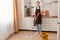 Full length portrait of attractive cheerful hardworking woman making fast domestic work, washing floor in modern light white