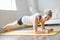 Full length portrait of attractive young woman working out at home in living room, doing yoga or pilates exercise