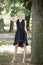 Full length portrait of beautiful barefooted young women wearing black dress while standing under pine tree