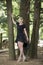 Full length portrait of beautiful barefooted young women wearing black dress while standing under pine tree