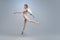 Full-length portrait of beautiful graceful ballerina dancing in image of angel with wings  on gray studio