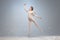 Full-length portrait of beautiful graceful ballerina dancing in image of angel with wings  on gray studio