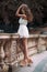 Full length portrait of beautiful model woman with long legs wearing white dress posing oudoors