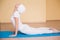 Full-length portrait of beautiful woman working out yoga excercise bhujangasana (cobra pose) on fitness mat