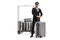 Full length portrait of a bellboy in a uniform standing with a suitcase in front of a luggage cart