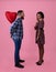 Full length portrait of black man with heart shaped balloon surprising girlfriend on Valentine's Day, pink background