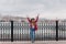 Full-length portrait of blissful caucasian lady in red jacket posing with hands up on embankment. Outdoor photo of