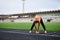 Full-length portrait of blond woman, doing stretching exercises on a stadium in summer, Fit sportswoman, wearing black leggings