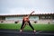 Full-length portrait of blond woman, doing stretching exercises on a stadium in summer, Fit sportswoman, wearing black leggings