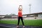 Full-length portrait of blond woman, doing stretching exercises on a stadium in summer, Fit sportswoman, wearing black leggings