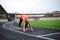 Full-length portrait of blond woman, ready to run on a stadium in summer, Fit sportswoman, wearing black leggings and orange top