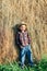 Full length portrait of boy in pose of lazy farmer, leaning hay