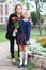 Full length portrait of Caucasian mother and schoolgirl in uniform going back to school, daughter holding flower