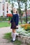 Full-length portrait of Caucasian schoolgirl in uniform going back to school, holding flowers in hand