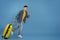 Full length portrait of cheerful male tourist with luggage running towards copy space over blue studio background