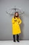 Full length portrait of a cheery girl dressed in raincoat