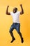 Full length portrait of a cherry young african american man listening to music with headphones and dancing isolated over