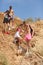 A full-length portrait of a company of smiling young people going down from a hill on a natural blurred background.