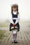 Full-length portrait of cute adorable first grader girl in school uniform and white bows with flowers basket composition standing