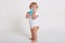 Full length portrait of cute toddler drinking water from bottle, one year old kid playing with baby cup, adorable curly hair boy