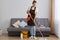 Full length portrait of dark haired woman wearing brown apron and casual clothing, washing floor with mop, doing household chores