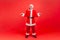 Full length portrait of elderly man with gray beard wearing santa claus costume shrugging