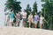 Full length portrait of excited overjoyed friends hold arms running sand beach have fun hanging out outdoors